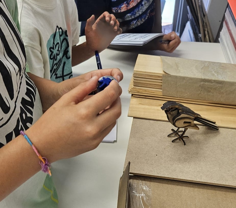 Manos de niños y niñas participando en el Taller Maker Nins