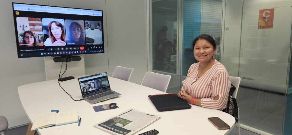 Jenny Campues en una mesa delante del ordenador y la pantalla de presentación de su charla